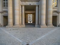 a courtyard with a building on the other side and a large white building with many windows