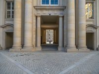 a courtyard with a building on the other side and a large white building with many windows