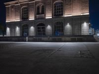 a building is lit up at night with the headlights on and a person walking past in front