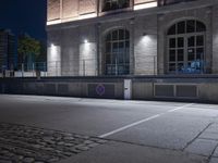 a building is lit up at night with the headlights on and a person walking past in front