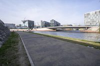 the asphalt road runs beside a river and buildings in the city setting at the top of each hill