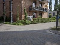 an apartment with brick facade on a sunny day on a sidewalk in front of building