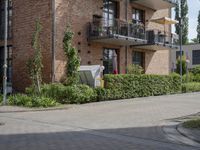 an apartment with brick facade on a sunny day on a sidewalk in front of building