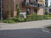 an apartment with brick facade on a sunny day on a sidewalk in front of building