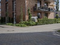 an apartment with brick facade on a sunny day on a sidewalk in front of building