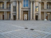 a courtyard with a building on the other side and a large white building with many windows