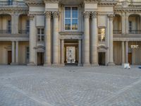 a courtyard with a building on the other side and a large white building with many windows