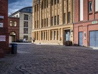 an empty cobblestone road lined with brick buildings on a street corner of town