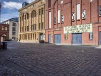 an empty cobblestone road lined with brick buildings on a street corner of town