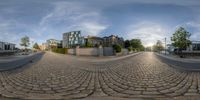 an upside down fisheye lens is shown over a cobblestone road with two buildings in the background