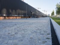 a brick building with glass windows and sidewalk leading to it and a black fire hydrant