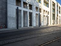 a street with a bike on the sidewalk in front of a building with windows and a woman in the foreground