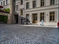 an empty parking lot with plants in the ground and on the side of the building, there is an enclosed area and windows