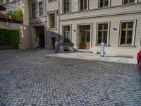 an empty parking lot with plants in the ground and on the side of the building, there is an enclosed area and windows