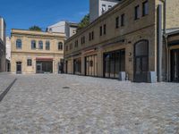 the sidewalk is paved with stones and has a bench in front of it, with no people inside