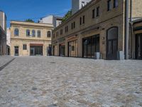 the sidewalk is paved with stones and has a bench in front of it, with no people inside