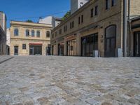 the sidewalk is paved with stones and has a bench in front of it, with no people inside