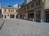 the sidewalk is paved with stones and has a bench in front of it, with no people inside