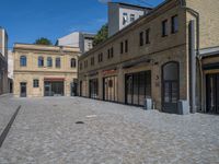 the sidewalk is paved with stones and has a bench in front of it, with no people inside