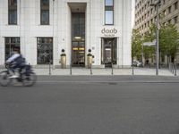 a man riding a bike in front of a building with a white door on the corner of the street