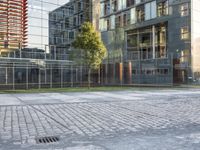 an empty paved square sits on a sidewalk in front of large buildings with glass facades