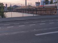 an open street with a large bridge in the background and buildings in the distance, including some traffic lights and stairs