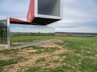 an upside down building in a grassy field on top of a hill with some grass