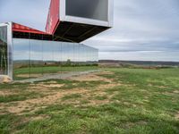 an upside down building in a grassy field on top of a hill with some grass