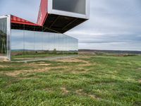 an upside down building in a grassy field on top of a hill with some grass