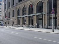 empty street with two signs in front of tall buildings in urban area with no people