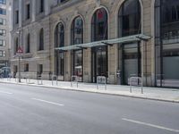 empty street with two signs in front of tall buildings in urban area with no people