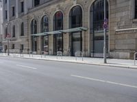 empty street with two signs in front of tall buildings in urban area with no people