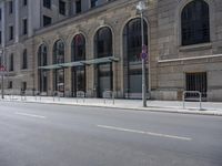 empty street with two signs in front of tall buildings in urban area with no people