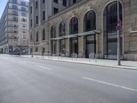 empty street with two signs in front of tall buildings in urban area with no people