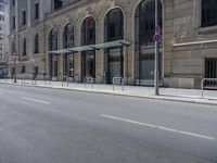 empty street with two signs in front of tall buildings in urban area with no people