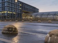 several concrete spheres in the rain and on an empty street with buildings in the background