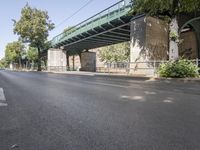 the bicycle is leaning on the side of the road next to the bridge above the empty road