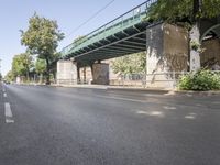 the bicycle is leaning on the side of the road next to the bridge above the empty road