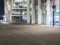 an empty city street in front of tall buildings at night time with no cars driving through