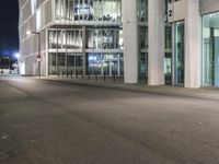 an empty city street in front of tall buildings at night time with no cars driving through