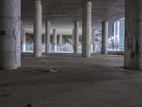 a empty parking garage filled with graffiti and a bunch of columns in it by some buildings