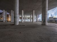 a empty parking garage filled with graffiti and a bunch of columns in it by some buildings