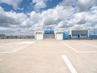 an empty parking lot with white painted lines and a large blue storage building behind it