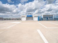 an empty parking lot with white painted lines and a large blue storage building behind it