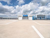 an empty parking lot with white painted lines and a large blue storage building behind it