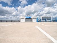 an empty parking lot with white painted lines and a large blue storage building behind it