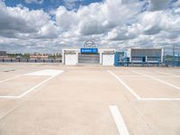 an empty parking lot with white painted lines and a large blue storage building behind it