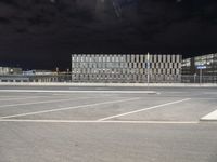 an empty parking lot with several flags and buildings in the background at night on a clear day