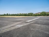 an empty parking lot with a sky background and trees lining the lot with houses behind