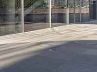 an empty patio with white tiled tiles and glass windows on either side of the sidewalk